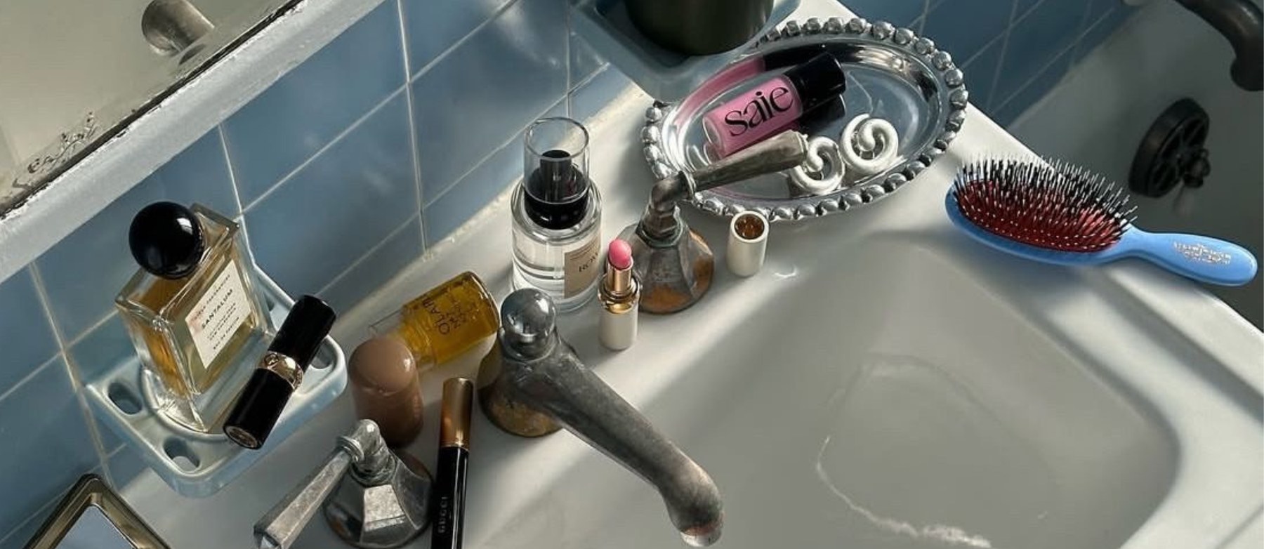 A bathroom sink covered in beauty products